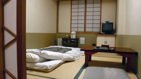 A traditional Japanese-style room with a futon bed on a tatami mat floor next to a low wooden table.