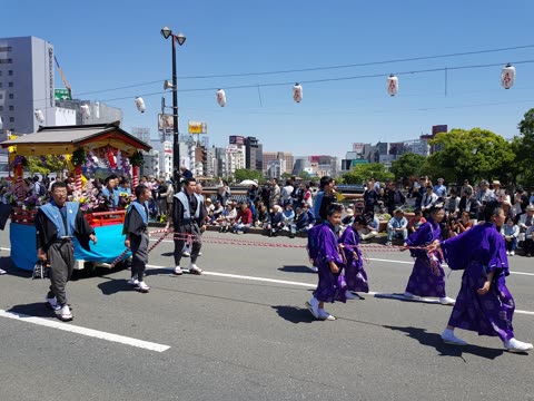 People pulling a decorated float in a city street parade.