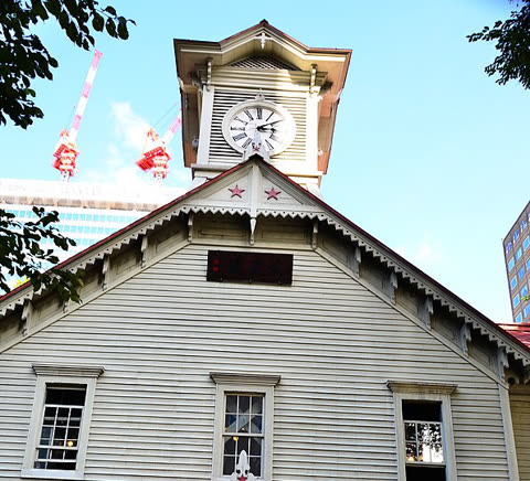 White clock tower with visible clock face and red stars, showing daytime.