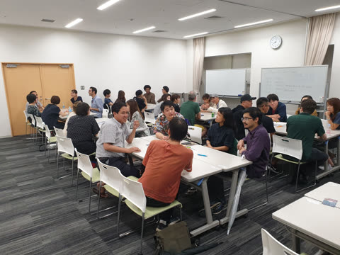 People converse at tables in a room.