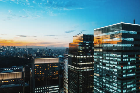 Aerial view of city skyline at sunset, showing illuminated skyscrapers.
