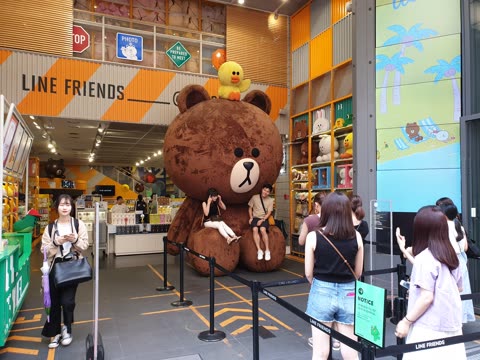 People sitting on a giant brown bear in a Line Friends store.