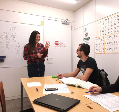 Woman demonstrates hand gesture in classroom.