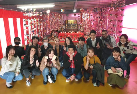 Group posing indoors surrounded by Hina Matsuri decorations.
